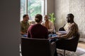 Diverse business meeting in modern open workspace with large windows and sunlight shining in