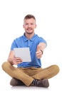 Casual seated young man with tablet shows thumb up