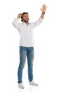 Casual Smiling Man Is Standing With Hand Raised, Looking Up And Waving Royalty Free Stock Photo