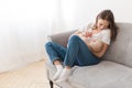 Happy woman cuddling with infant on sofa