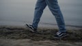 Casual sneakers walking on sea shore closeup. Man feet enjoying walk on beach Royalty Free Stock Photo