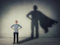 Casual teenage, keeps arms on hips smiling confident, casting a superhero with cape shadow on the wall. Student ambition success Royalty Free Stock Photo