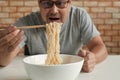 Casual Thai man uses chopsticks to eat instant noodles in a white cup Royalty Free Stock Photo