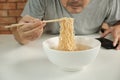 Casual Thai man uses chopsticks to eat instant noodles in a white cup Royalty Free Stock Photo