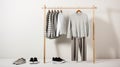 Casual white and grey clothing on a wooden clothes rack. Striped and plain shirts, pants, and shoes, on white background with copy Royalty Free Stock Photo