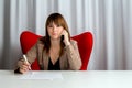 Casual woman at office writing with pen and talking by phone Royalty Free Stock Photo