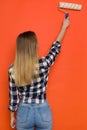 Casual Woman Painting Orange Wall. Rear View
