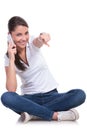 Casual woman sits & points on phone Royalty Free Stock Photo