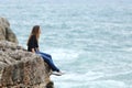 Casual woman sitting in a cliff watching the sea