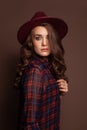 Casual woman wearing fedora hat on brown background