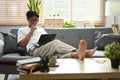 Casual asian man relaxing on couch and surfing internet with digital tablet. Royalty Free Stock Photo