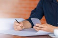 Casual young business man hand using mobile smart phone with silver pen and coffee blurred background Royalty Free Stock Photo