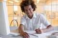 Casual young businessman writing at his desk smiling at camera Royalty Free Stock Photo