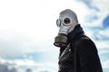 Casual young man in a gas mask standing on the street in an empty city