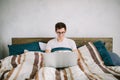 Casual young man using laptop in bed at home Royalty Free Stock Photo