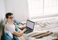 Casual young man using laptop in bed at home Royalty Free Stock Photo