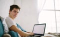 Casual young man using laptop in bed at home Royalty Free Stock Photo