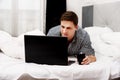 Casual young man using laptop in bed at home. Royalty Free Stock Photo