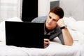 Casual young man using laptop in bed at home. Royalty Free Stock Photo