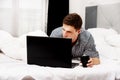 Casual young man using laptop in bed at home. Royalty Free Stock Photo