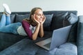 Casual young woman lying on couch and using laptop at home Royalty Free Stock Photo