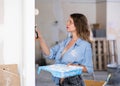Casual young woman painting walls with a paint roller in refurbished room Royalty Free Stock Photo