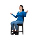 Casual young woman sitting on a chair, eyes closed, hands showing zen gesture like practicing yoga isolated over white background Royalty Free Stock Photo