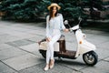 Young woman sitting on moto scooter on narrow street in old town.