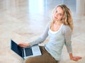 Casually connected - Laptop technology. A cute young blonde sitting on the floor and browsing her laptop.