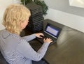 A casually dressed caucasian middle aged woman is installing a laptop computer with a stack of several more computers