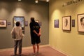 Casually dressed couple standing in front of framed images depicting the war, National WWII Museum, New Orleans, 2016