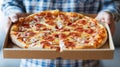 Casually dressed man holding italian pizza in flat box with space for text message. Royalty Free Stock Photo