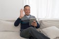 A casually dressed man sits comfortably on a plush grey couch, his attitude relaxed yet focused. His eyes are warm, inviting and Royalty Free Stock Photo