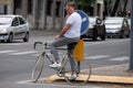 Casually Dressed Man waits for the Cars to pass Before Crossing the Street with traffic with his New Bicycle