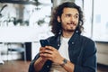 Casually dressed young businessman using mobile phone in office Royalty Free Stock Photo