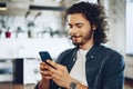 Casually dressed young businessman using mobile phone in office Royalty Free Stock Photo