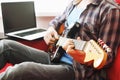 Casually dressed young man with guitar playing songs in the room at home. Online guitar lessons concept. Male guitarist practicing Royalty Free Stock Photo