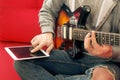 Casually dressed young man with guitar playing songs in the room at home. Online guitar lessons concept. Male guitarist practicing Royalty Free Stock Photo