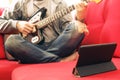 Casually dressed young man with guitar playing songs in the room at home. Online guitar lessons concept. Male guitarist practicing Royalty Free Stock Photo