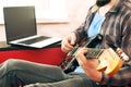 Casually dressed young man with guitar playing songs in the room at home. Online guitar lessons concept. Male guitarist practicing Royalty Free Stock Photo