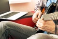 Casually dressed young man with guitar playing songs in the room at home. Online guitar lessons concept. Male guitarist practicing Royalty Free Stock Photo