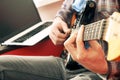 Casually dressed young man with guitar playing songs in the room at home. Online guitar lessons concept. Male guitarist practicing Royalty Free Stock Photo