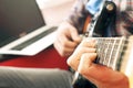 Casually dressed young man with guitar playing songs in the room at home. Online guitar lessons concept. Male guitarist practicing Royalty Free Stock Photo