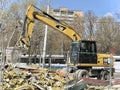 Cat backhoe loader performs demolition work on a building on a city street