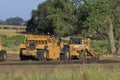 An CAT Earth Mover and CATERPILLAR sitting at a work site with dirt, tree\'s and blue sky