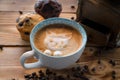 Cat foam face of latte art coffee in cup with scattered coffee beans and biscuits on old wooden table Royalty Free Stock Photo