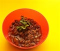 Cat food with jelly in a little orage bowl on a yellow background