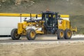 A CAT heavy industrial yellow motor grader on a construction site