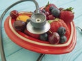 Cat homeless eats on the streetfruit strawberry, antioxid sweet blueberry, cherry, apricot plate heart on blue wooden, stethoscope Royalty Free Stock Photo