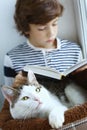 Cat lay in pet bed with boy reading book Royalty Free Stock Photo